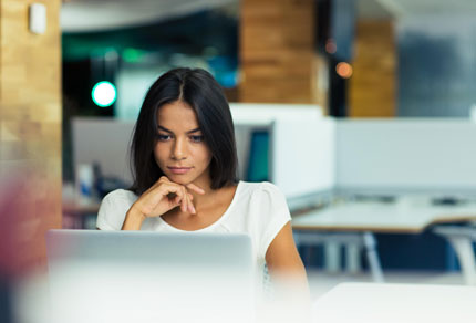 A business woman using a laptop in an office.