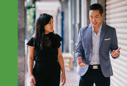 Two business people walking and talking outside.