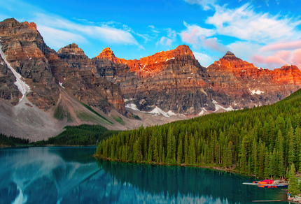 Moraine Lake surrounded by forested mountains in Alberta’s Canadian Rockies at sunset.