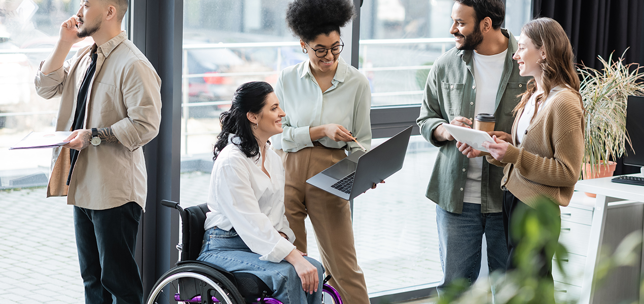 A diverse group of people of different races and abilities having a discussion in an office.