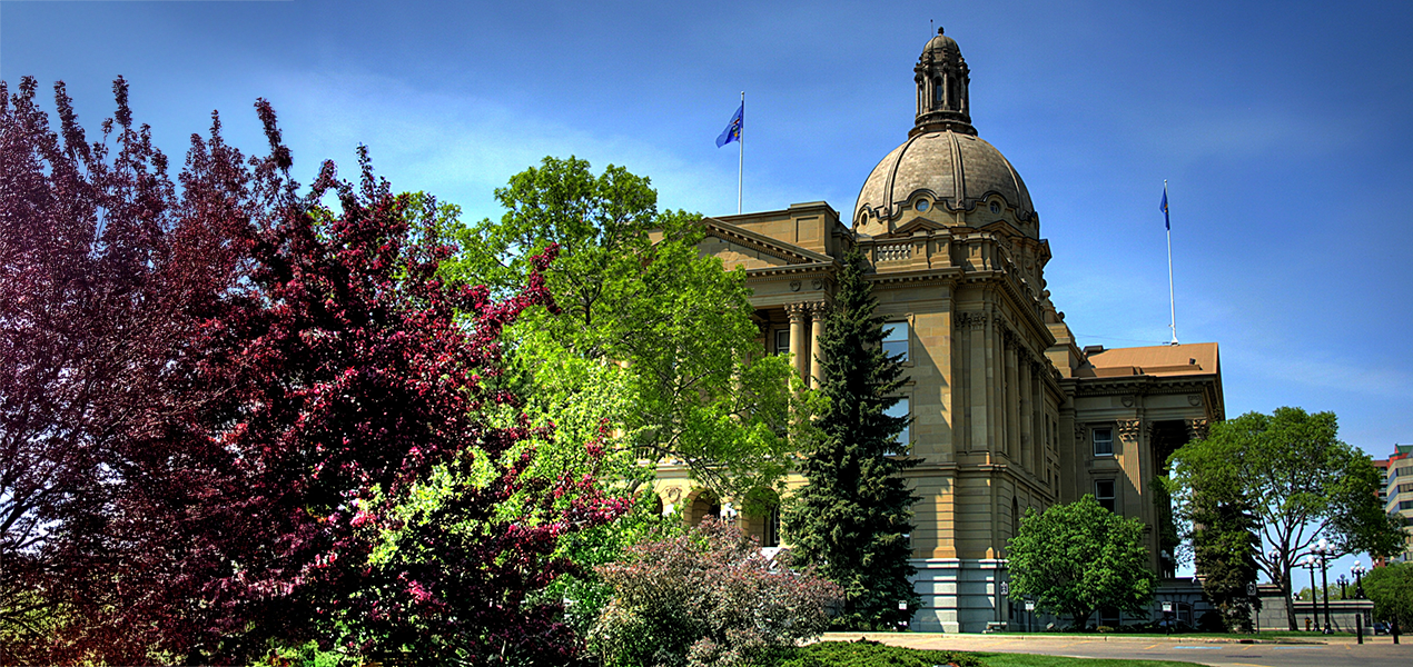 The Alberta Legislature building, frames by red and green bushes