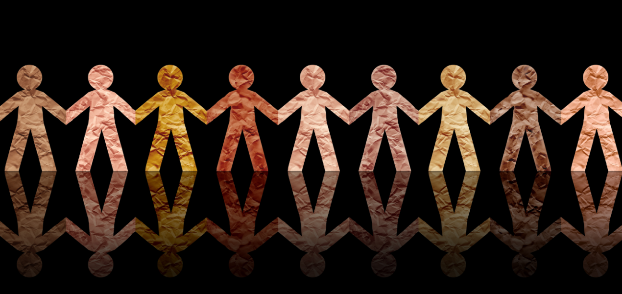 A chain of paper dolls of various skins tones holding hands.
