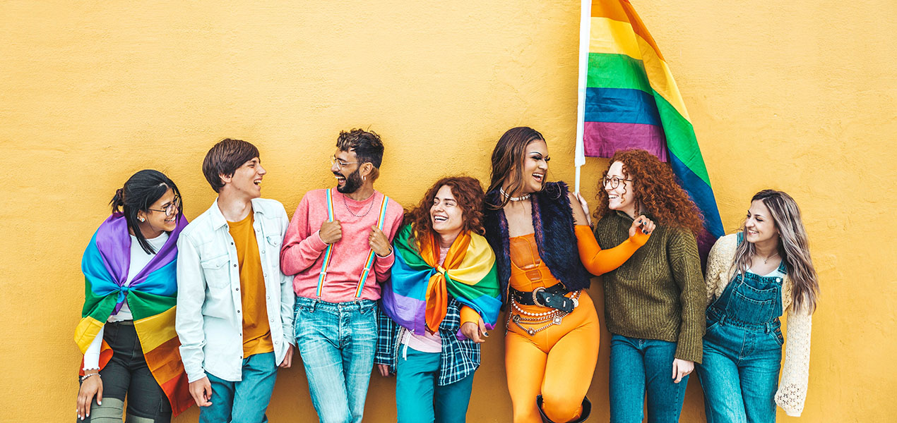 Group of young people standing against wall celebrating LGBTQ community.