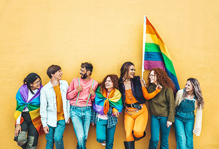 Group of young people standing against wall celebrating LGBTQ community.